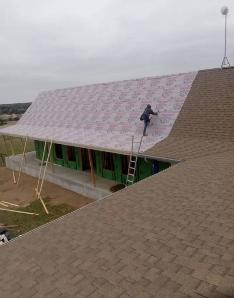 Worker preparing underlayment for a metal roof installation in Woodland